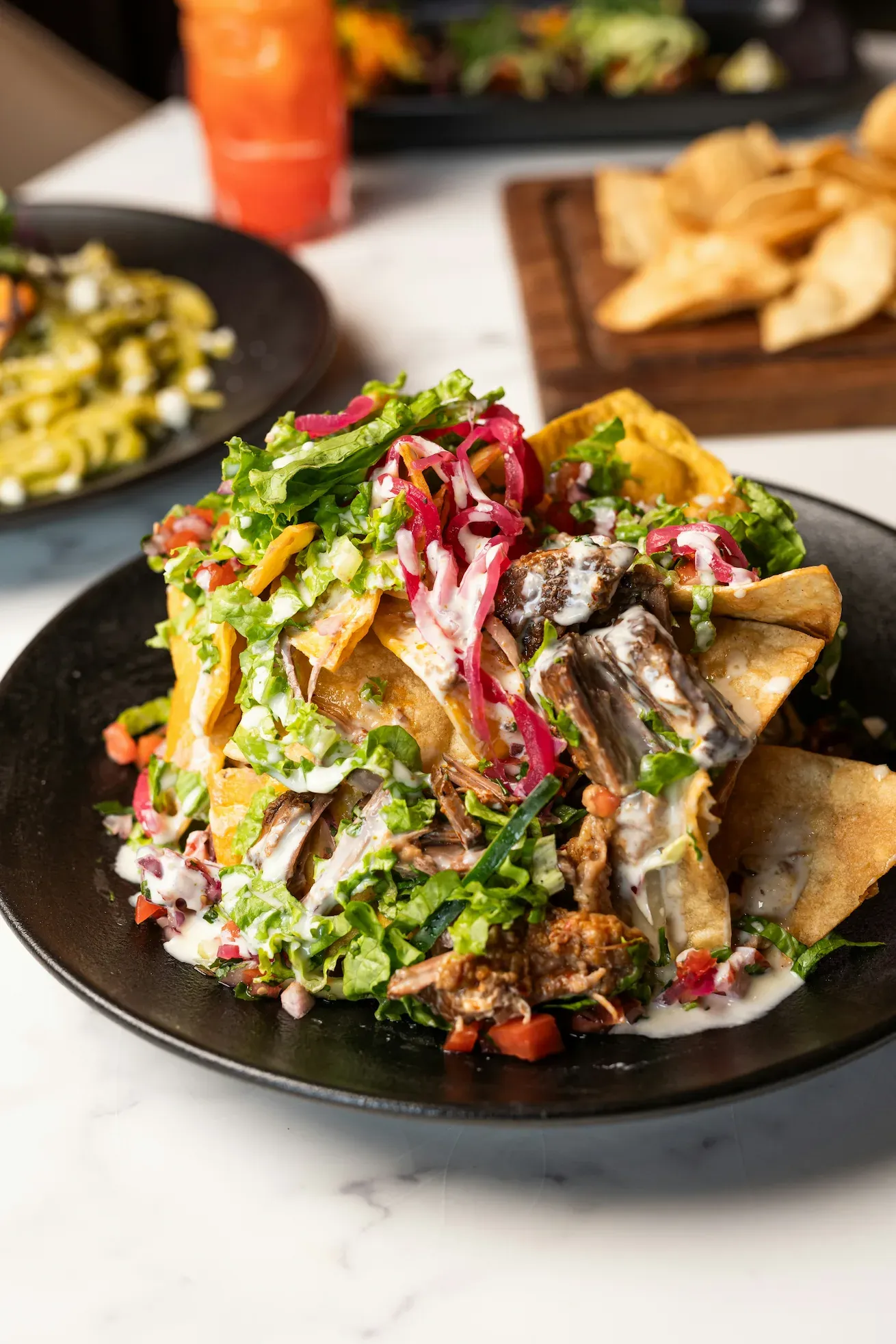 Nachos de Barbacoa — House-made chips, barbacoa, pico de gallo, crema, pickled onion.